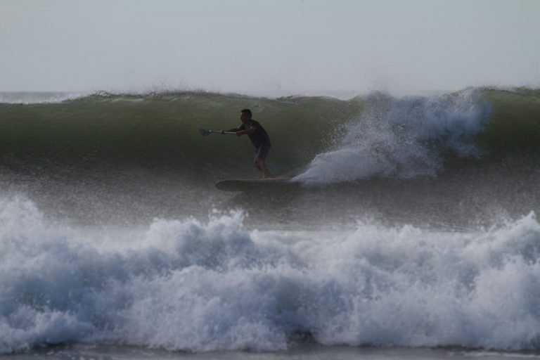 Harris surfing his otter wooden paddleboard