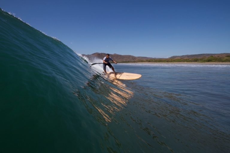 Harris surfing his otter wooden paddleboard