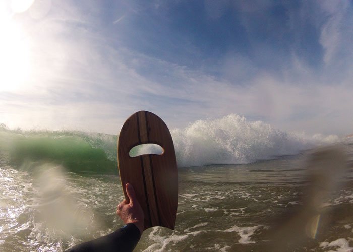 otter wooden handplane in the shorebreak