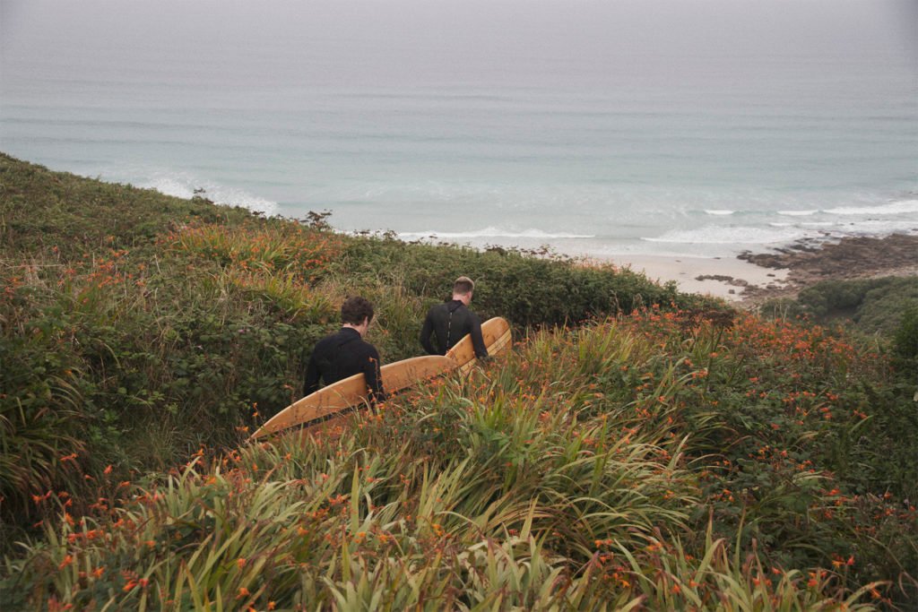 James Otter and Sean walking to the beach with their wooden surfboards