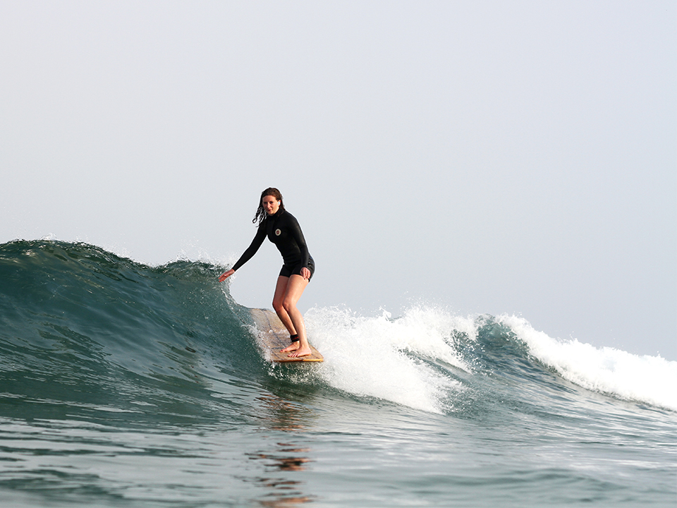 becky riding an otter surfboards wooden longboard at penhale