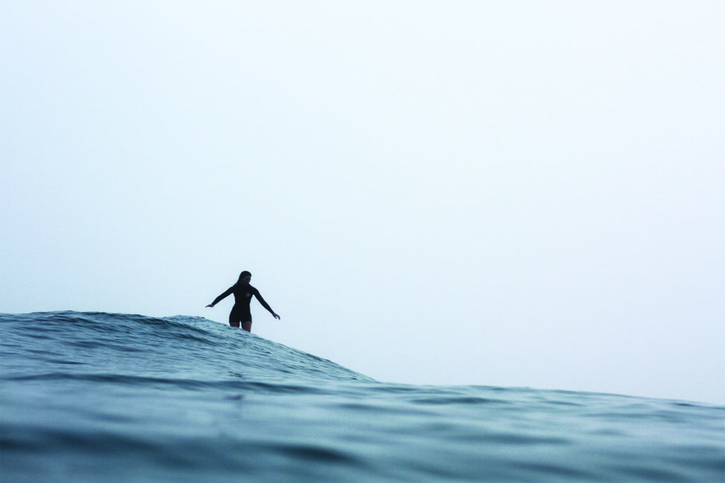 Becky gliding along a wave in the mist on the Otter Surfboards wooden Seasaw model