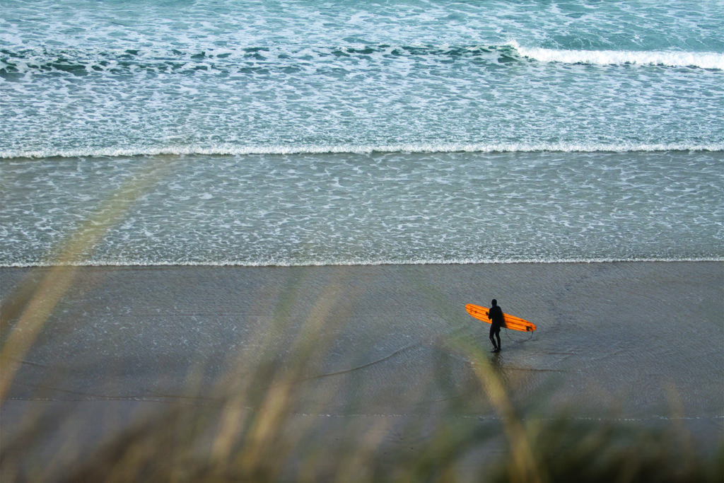 Mat Arney Looking back on the surf with the Otter Surfboards Pier wooden surfboard.