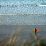 Mat Arney Looking back on the surf with the Otter Surfboards Pier wooden surfboard.