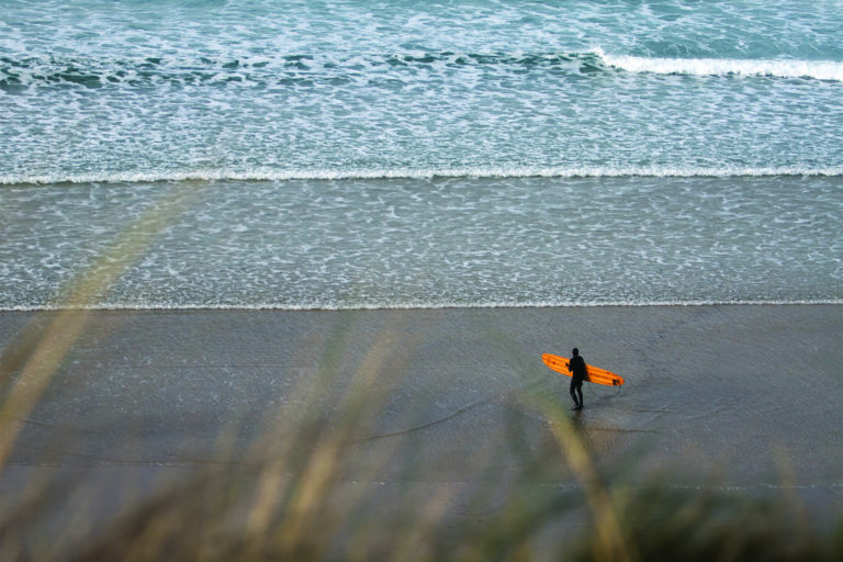 Mat Arney Looking back on the surf with the Otter Surfboards Pier wooden surfboard.