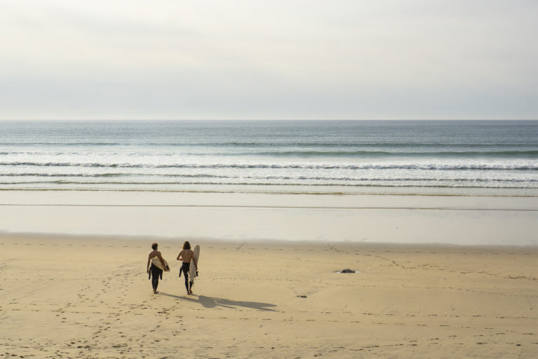 Chris and Larry walk to the waves in high summer with their Otter Wooden Surfboards at Gwithian in Cornwall. Riser and Coaster