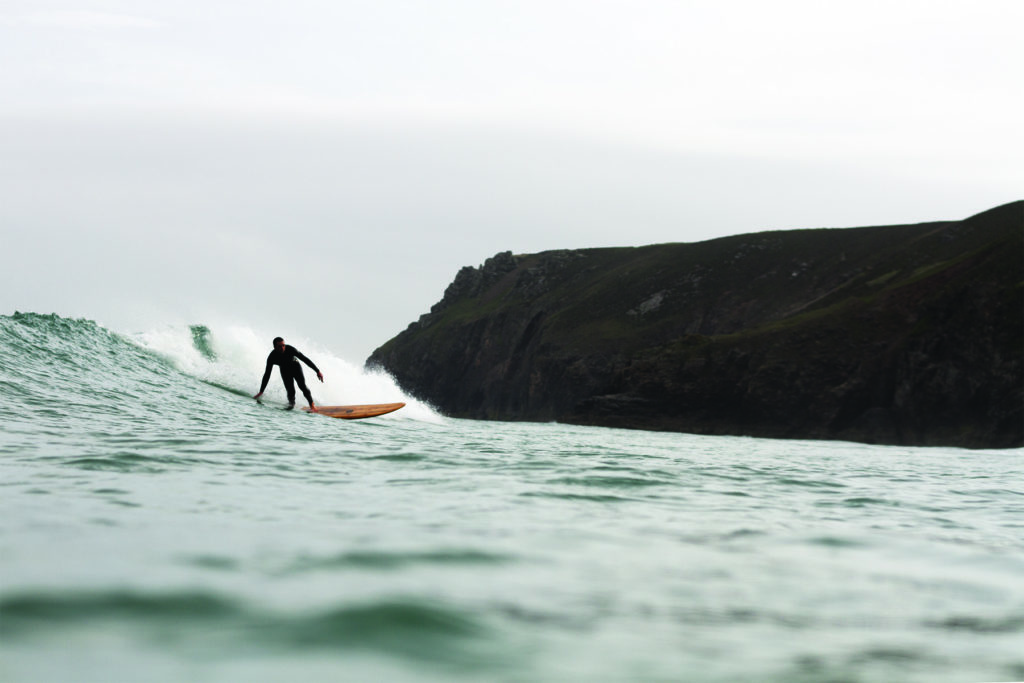 Chris bottom turning the Pier and Chapel Porth, Cornwall. Otter wooden surfboard