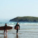 James Otter and Becky exit the surf at Perranporth, Cornwall with their wooden surfboards. Seasaw and Seadar
