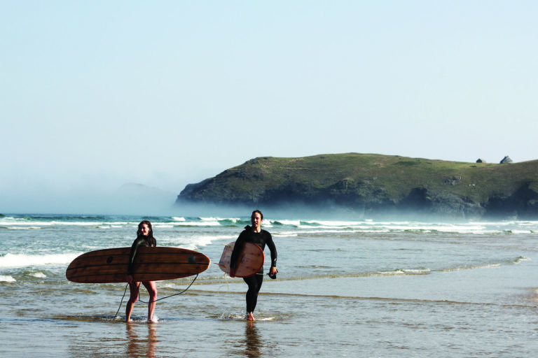 James Otter and Becky exit the surf at Perranporth, Cornwall with their wooden surfboards. Seasaw and Seadar