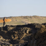 Chris walks back up the cliff with the Otter Surfboards wooden longboard Seasaw at Godrevy