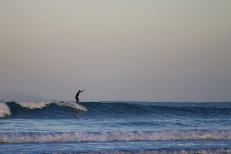 Chris runs to the nose arms up on the Otter Surfboards wooden longboard Seasaw at Godrevy
