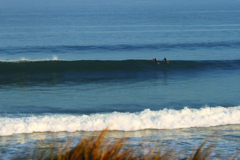 Chris and Gideon paddle over a wave with Otter Surfboards wooden Island Hopper and Jetty at Gwithian