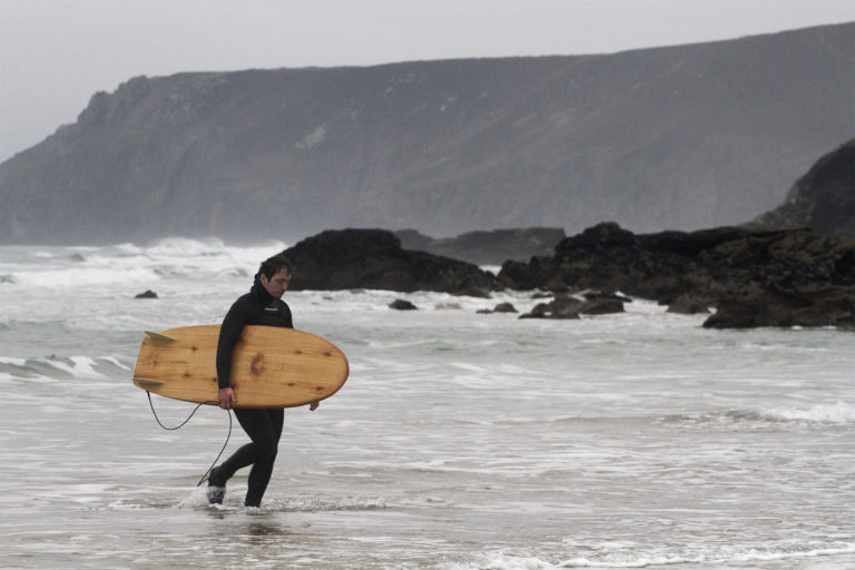 Seadar James Otter Surfing wooden surfboard at Porthtowan walking out