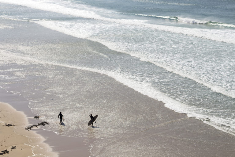 James Otter and Tom with wooden surfboards on the coast in Cornwall Wicket and Coaster silhouettes in summer