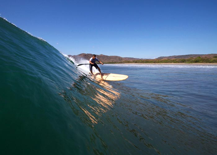 Haris surfing his wooden stand up paddle board Otter Surfboards