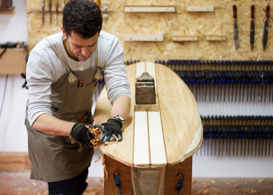 Jonathan shaping the rails of his wooden surfboard in the otter workshop
