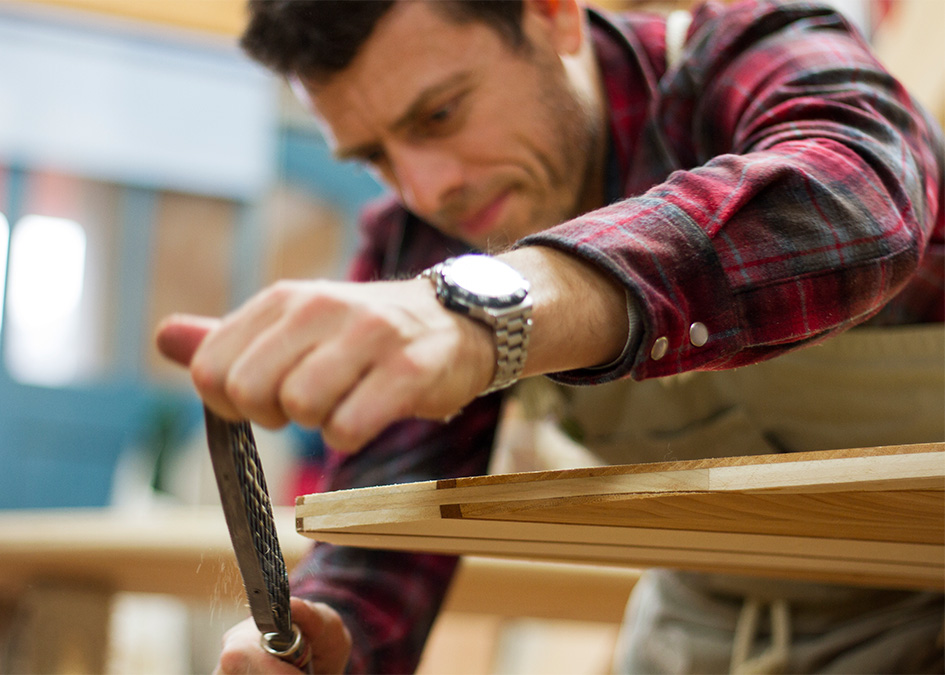 Jonathan rasping the tail of his wooden surfboard in the otter workshop
