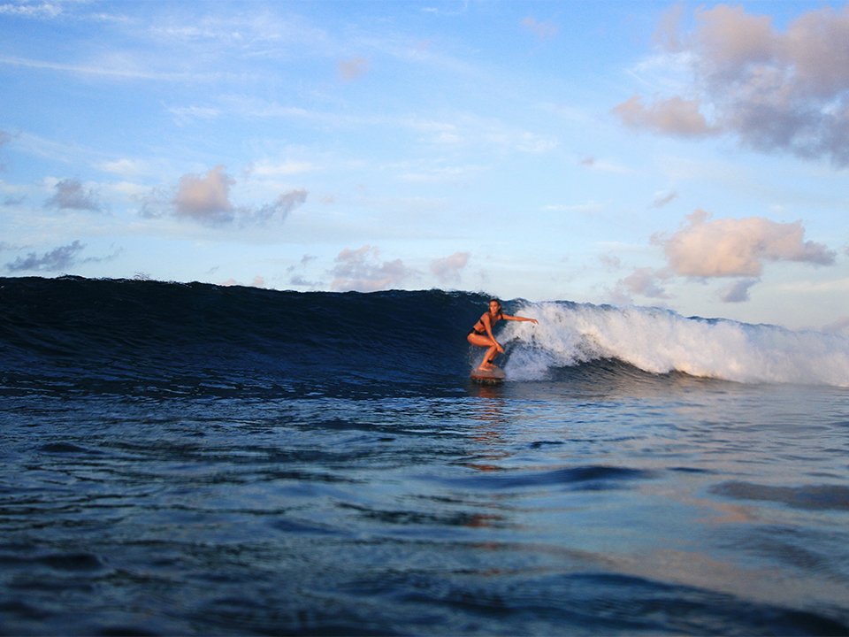 Sophie Hellyer on the beach in wetsuit with otter wooden surfboard in maldives seadar