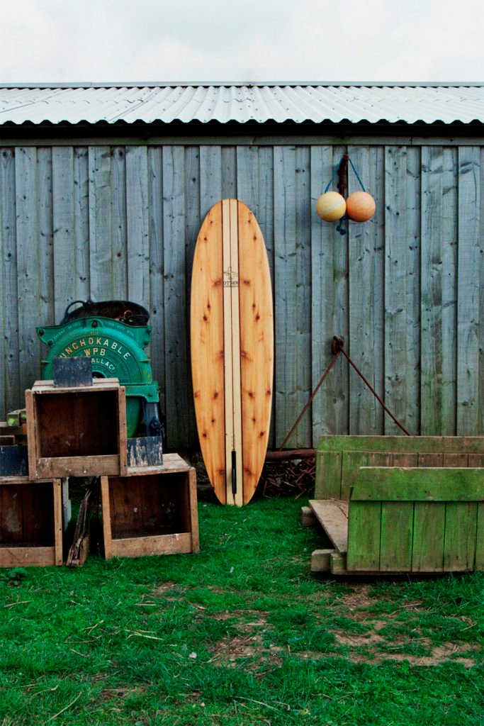 The Storyboard by James Otter and Mat Arney Wooden Surfboard Project wooden surfboard leans against barn