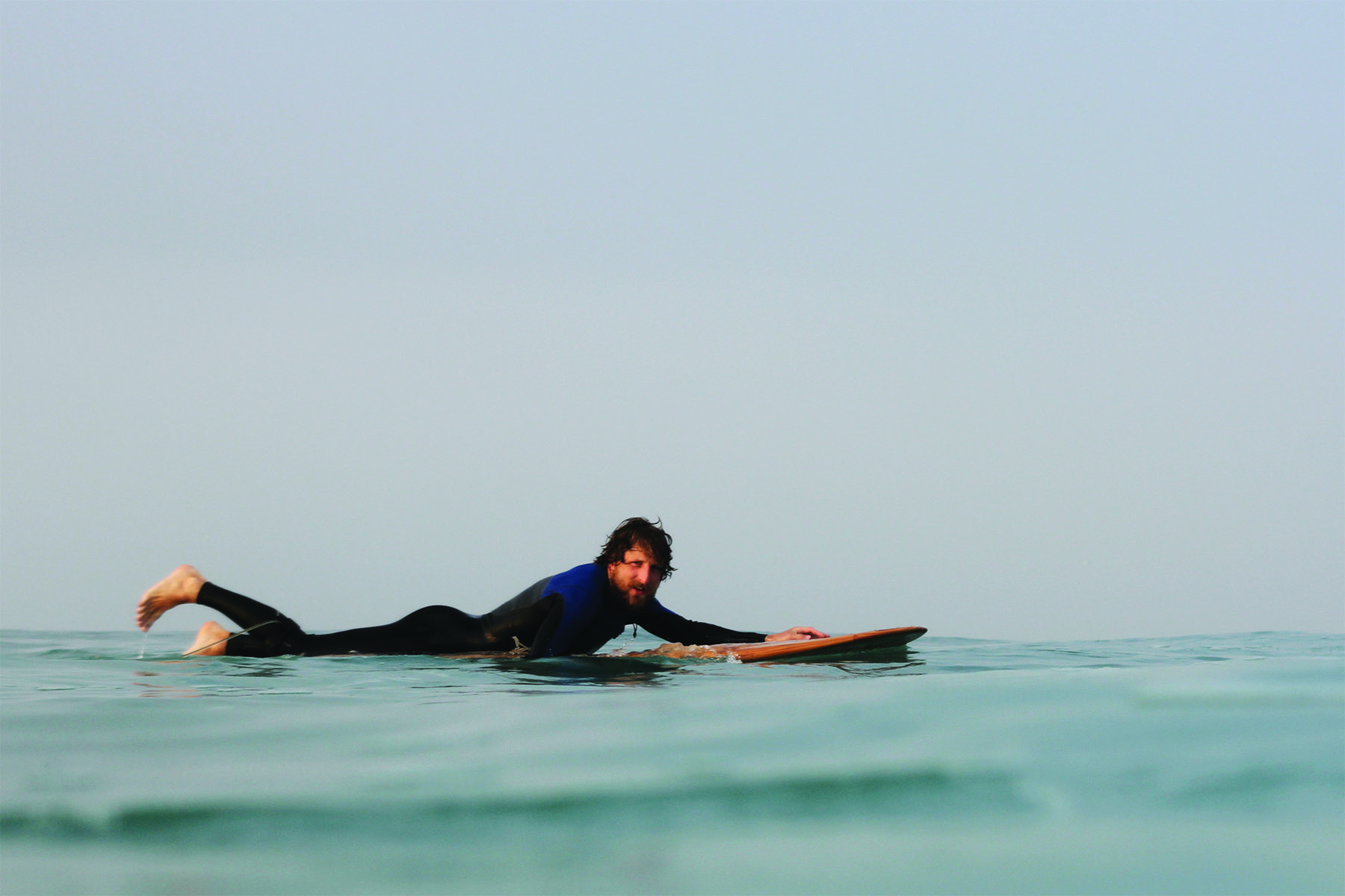 Chris brunt paddling an otter wooden surfboard longboard