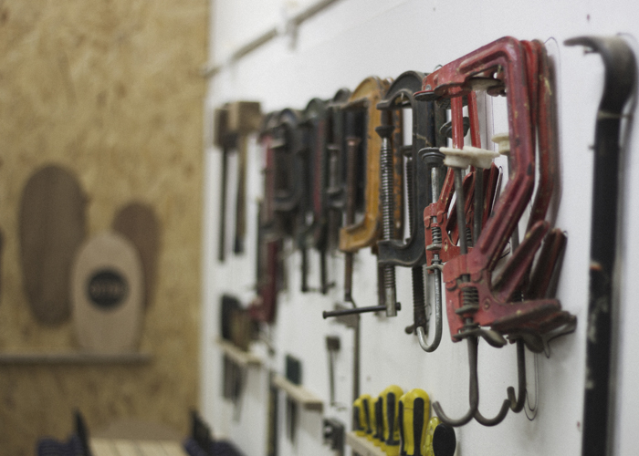 otter surfboards clamps on a wall in the workshop