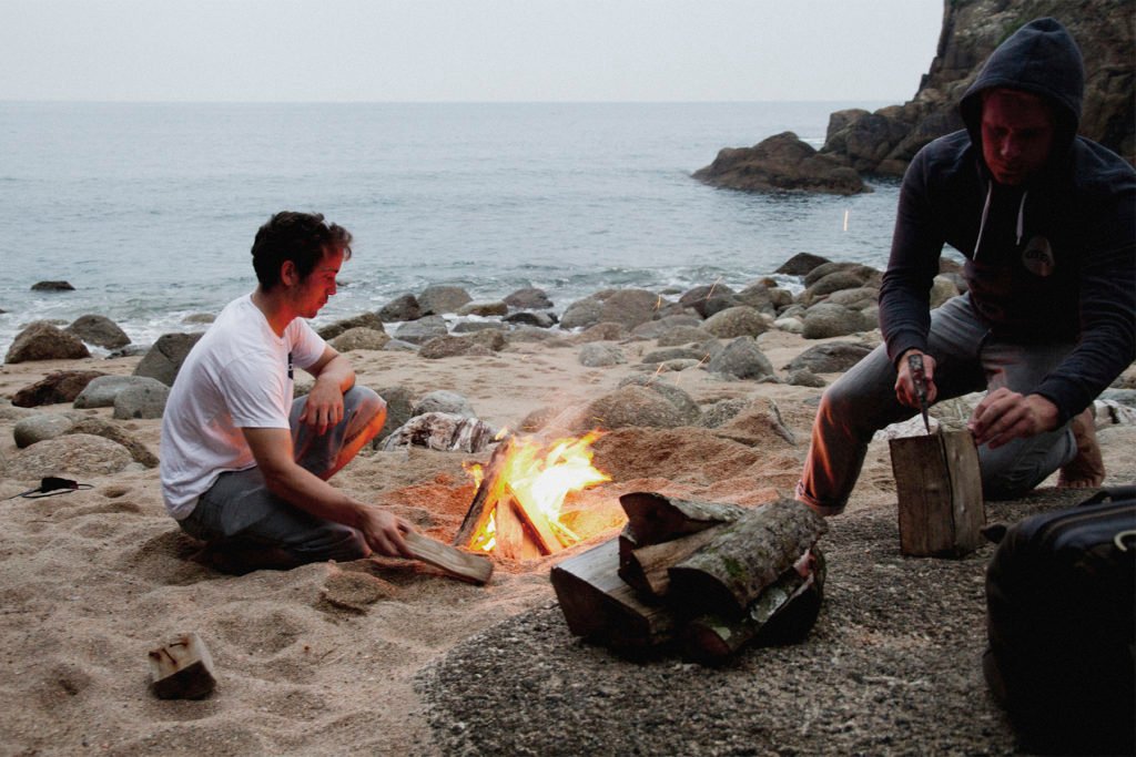 sean and james making a beach fire in cornwall