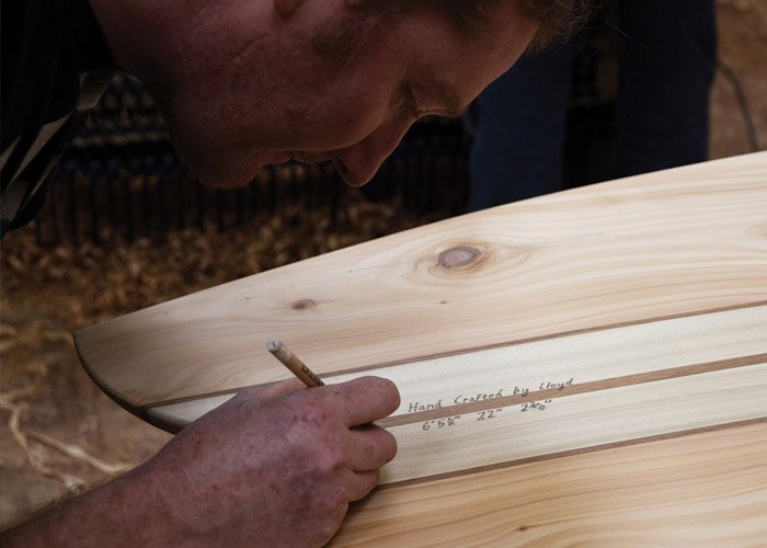 lloyd signing off his otter wooden surfboard