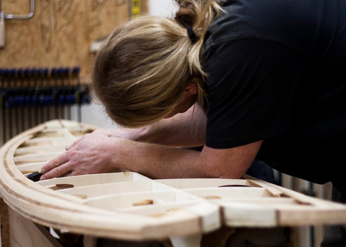 lloyd chiseling glue from hims wooden surfboard in the otter workshop