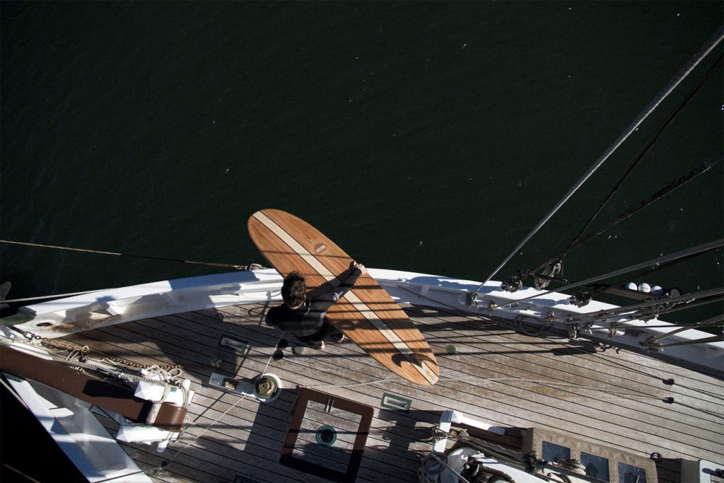 Otter wooden surfboard on gunwhale of wooden pilot cutter boat