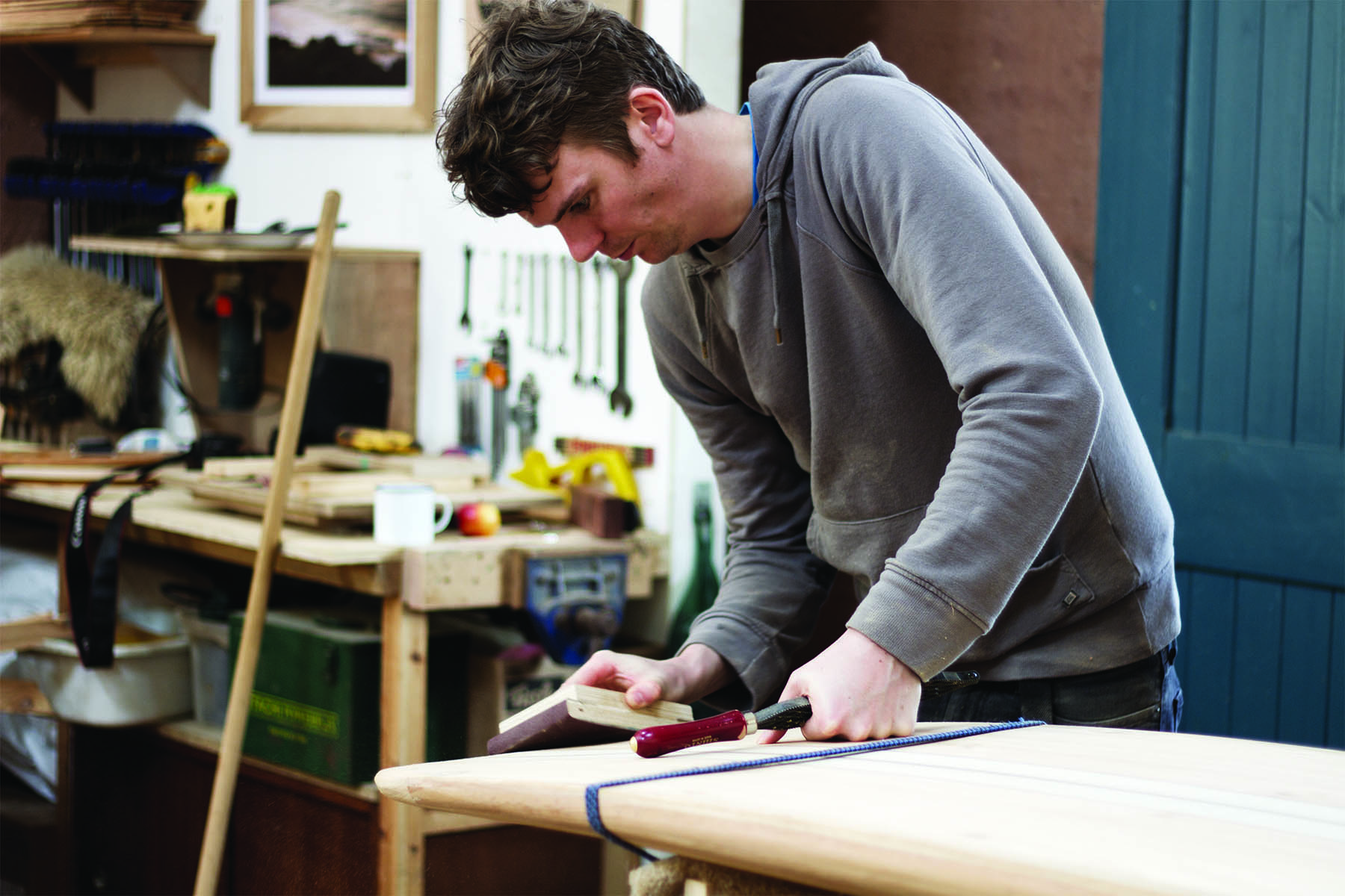Claudio Pete and Patrick making wooden surfboards in the otter workshop patrick sanding tail