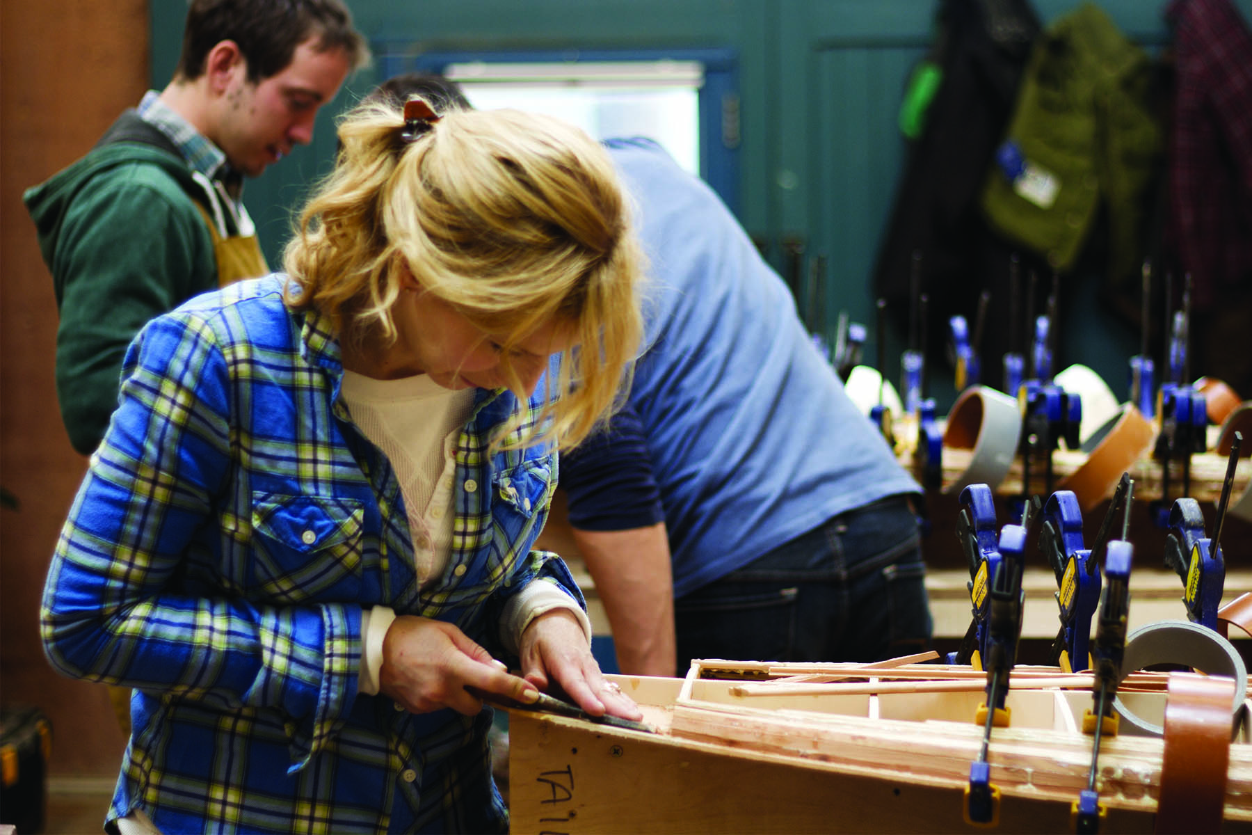 shelby chiseling for tail block on her wooden surfboard in the otter workshop