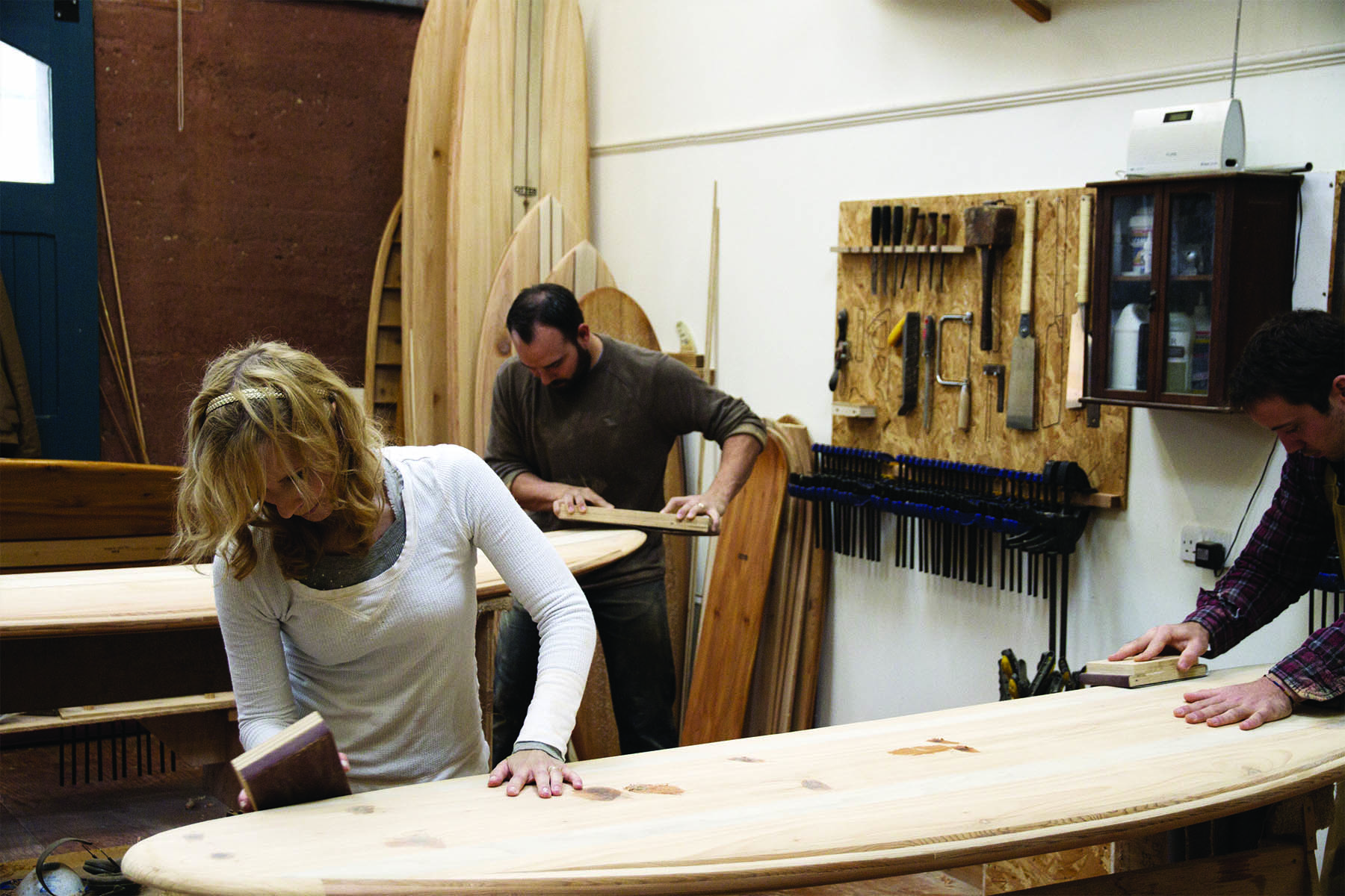 Kim and Shelby wooden surfboard making in the otter workshop in cornwall sanding time