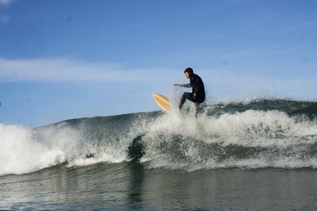 Surfer on a sustainable, hollow wooden surfboard.